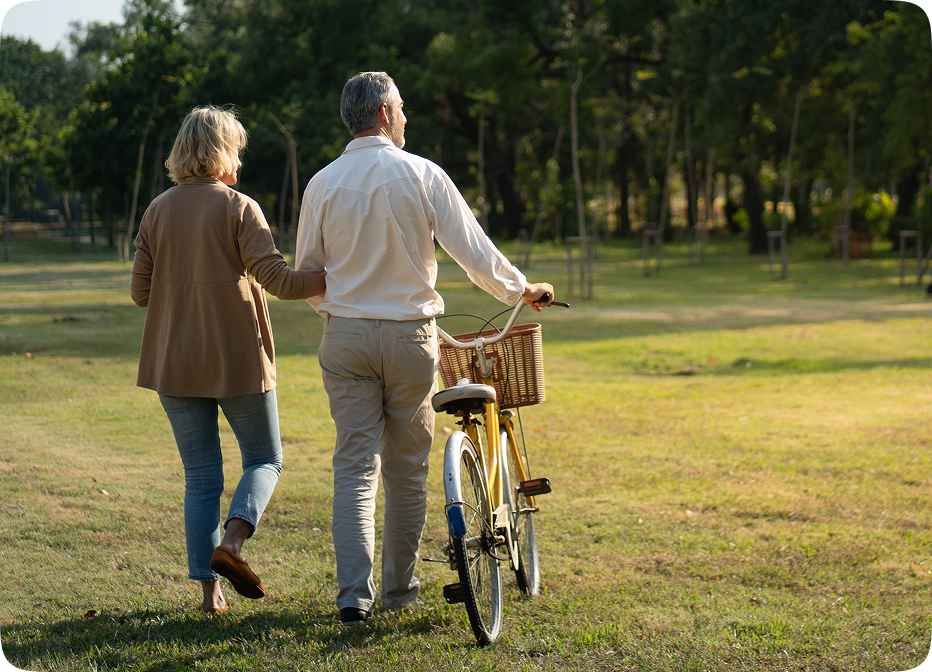Senior couple walking outdoors with bicycle, representing active lifestyle supported by Audien hearing aids