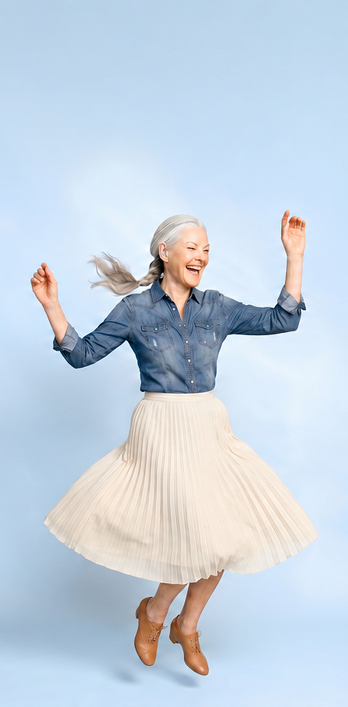 Woman in a denim shirt and white skirt dancing against a light blue background